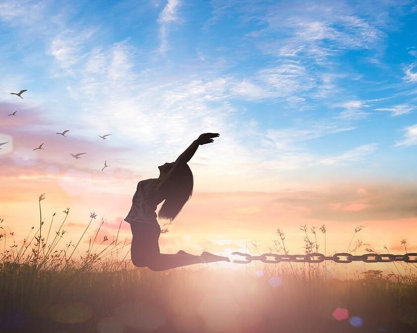 silhouette of woman celebrating by jumping in field presumably because of healing after trauma