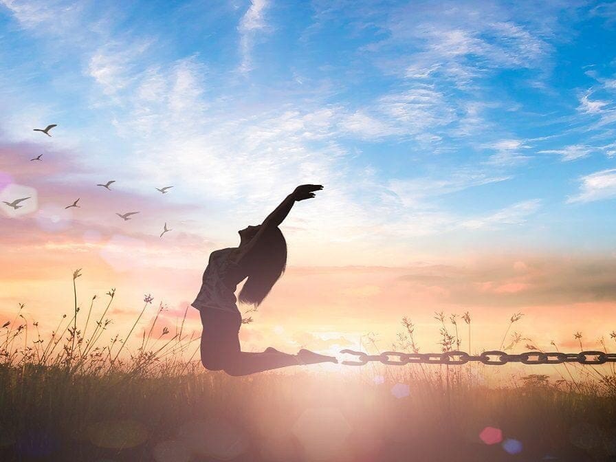 silhouette of woman celebrating by jumping in field presumably because of healing after trauma