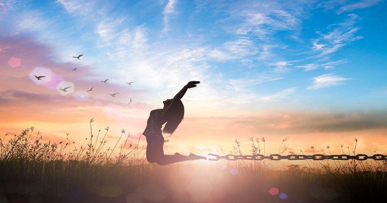 silhouette of woman celebrating by jumping in field presumably because of healing after trauma