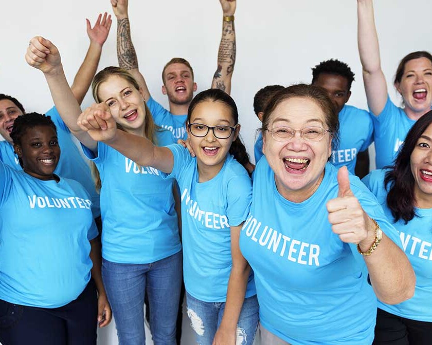 Volunteers in blue shirts smiling and serving like Jesus