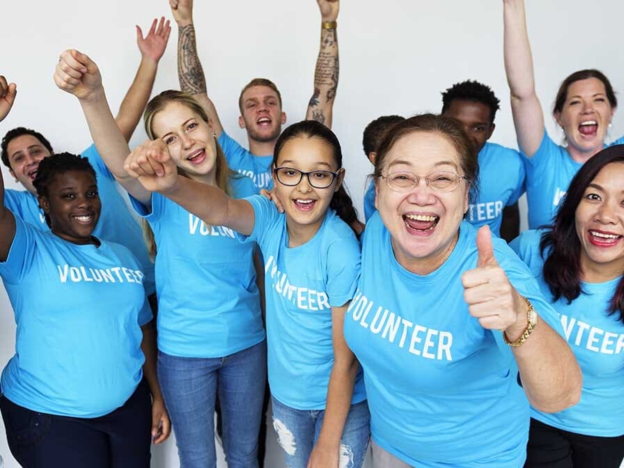 Volunteers in blue shirts smiling and serving like Jesus