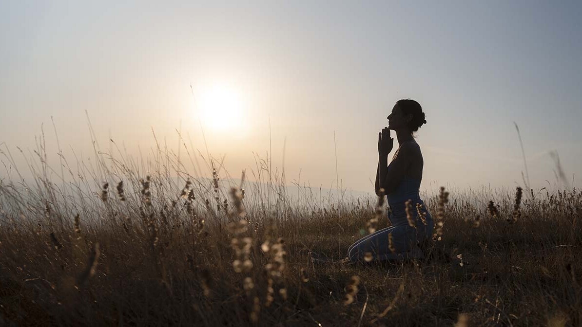 Silhouette of woman praying at sunset, expressing true repentance and seeking God