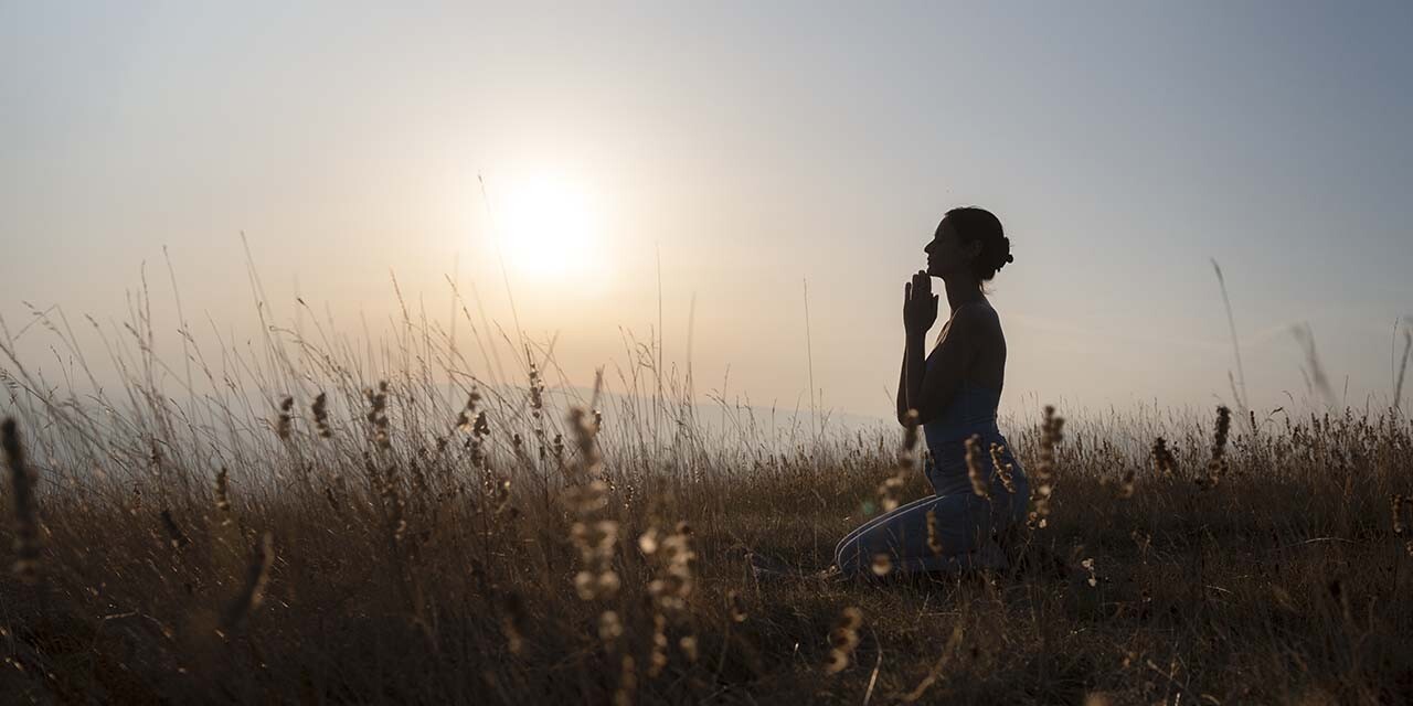 Silhouette of woman praying at sunset, expressing true repentance and seeking God