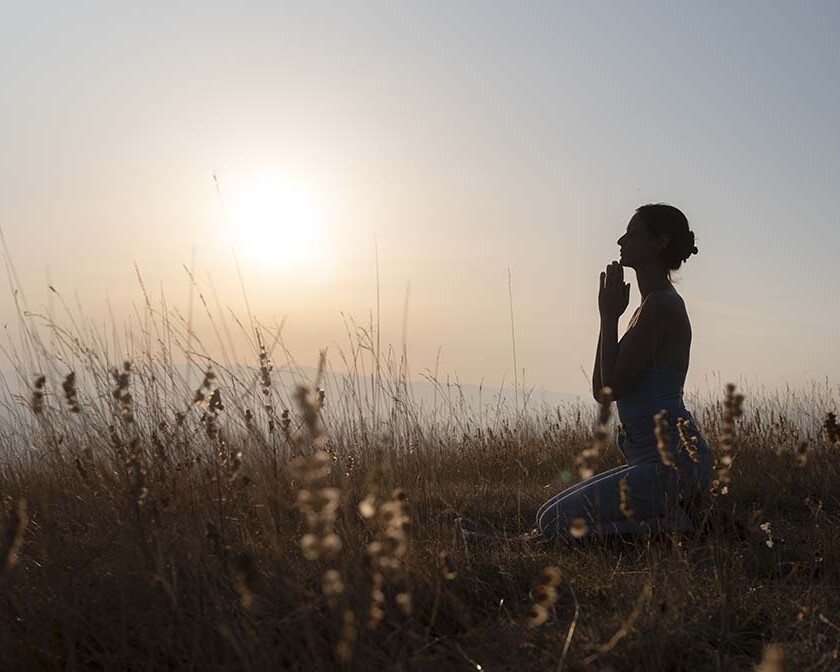 Silhouette of woman praying at sunset, expressing true repentance and seeking God