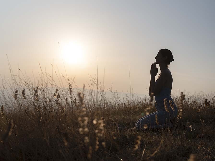 Silhouette of woman praying at sunset, expressing true repentance and seeking God