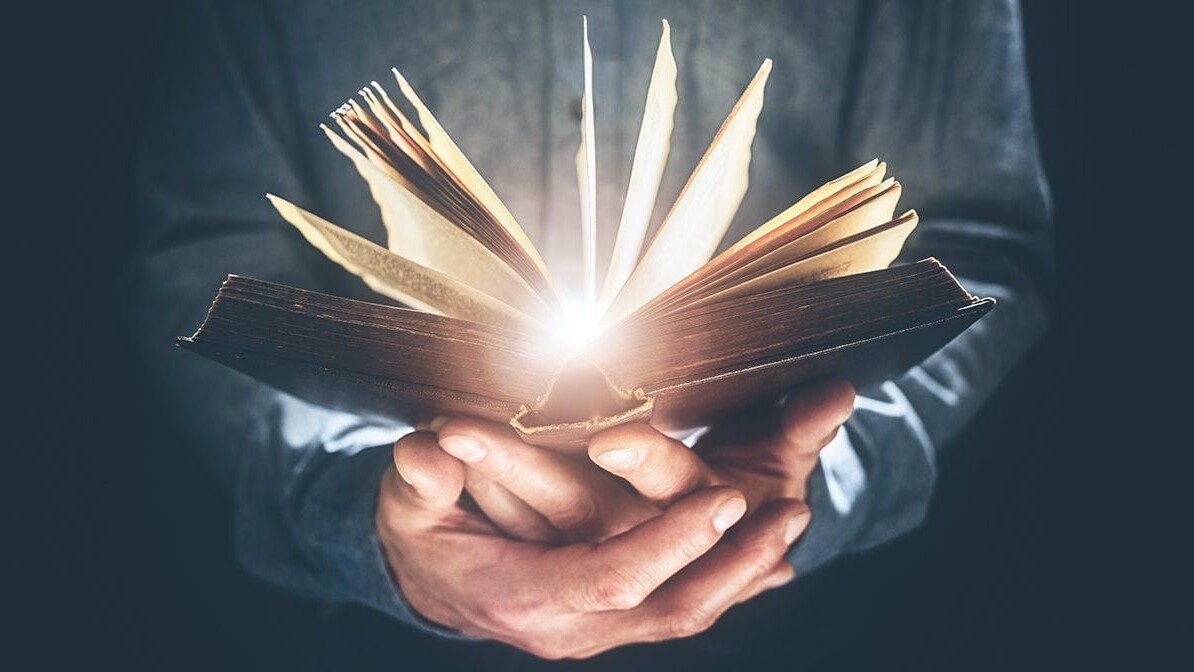 A person's hands holding an open Bible with glowing light radiating from the pages, illustrating the power of a daily Bible reading habit.