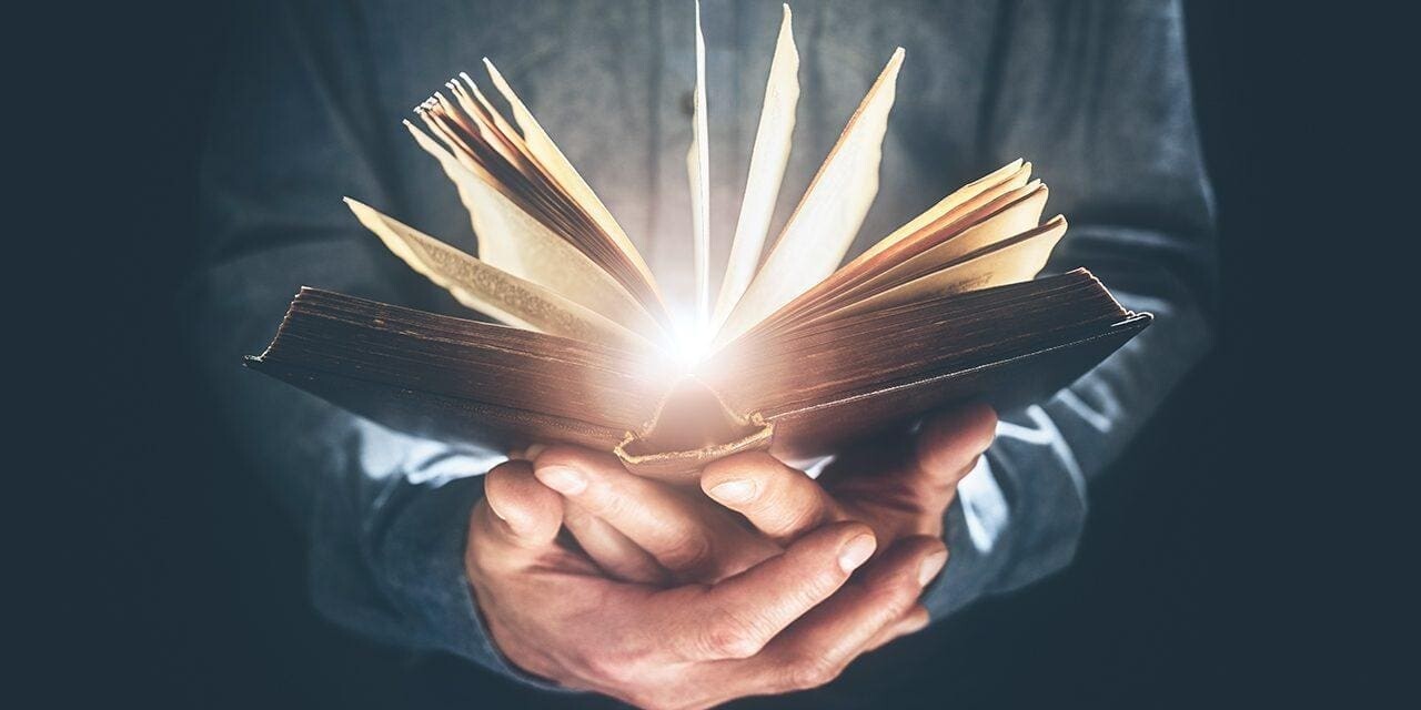 A person's hands holding an open Bible with glowing light radiating from the pages, illustrating the power of a daily Bible reading habit.