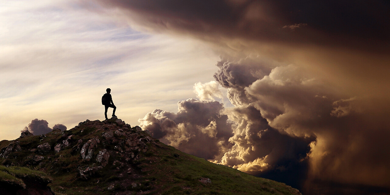 man standing on mountain looking at dark clouds; 3 biblical keys to spiritual power