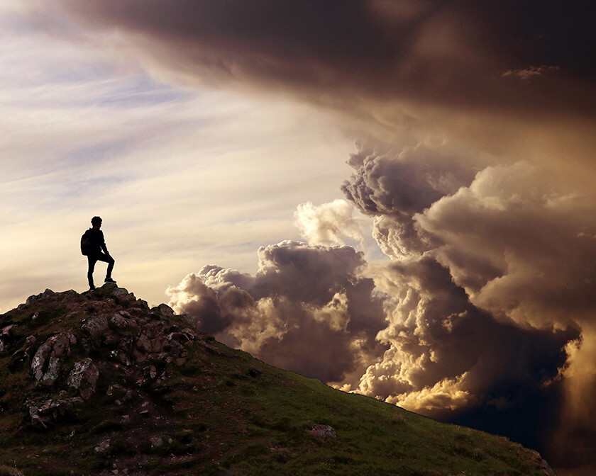 man standing on mountain looking at dark clouds; 3 biblical keys to spiritual power