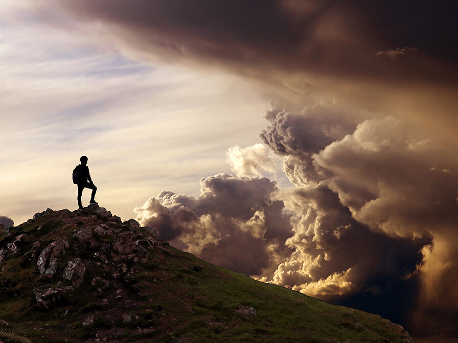 man standing on mountain looking at dark clouds; 3 biblical keys to spiritual power