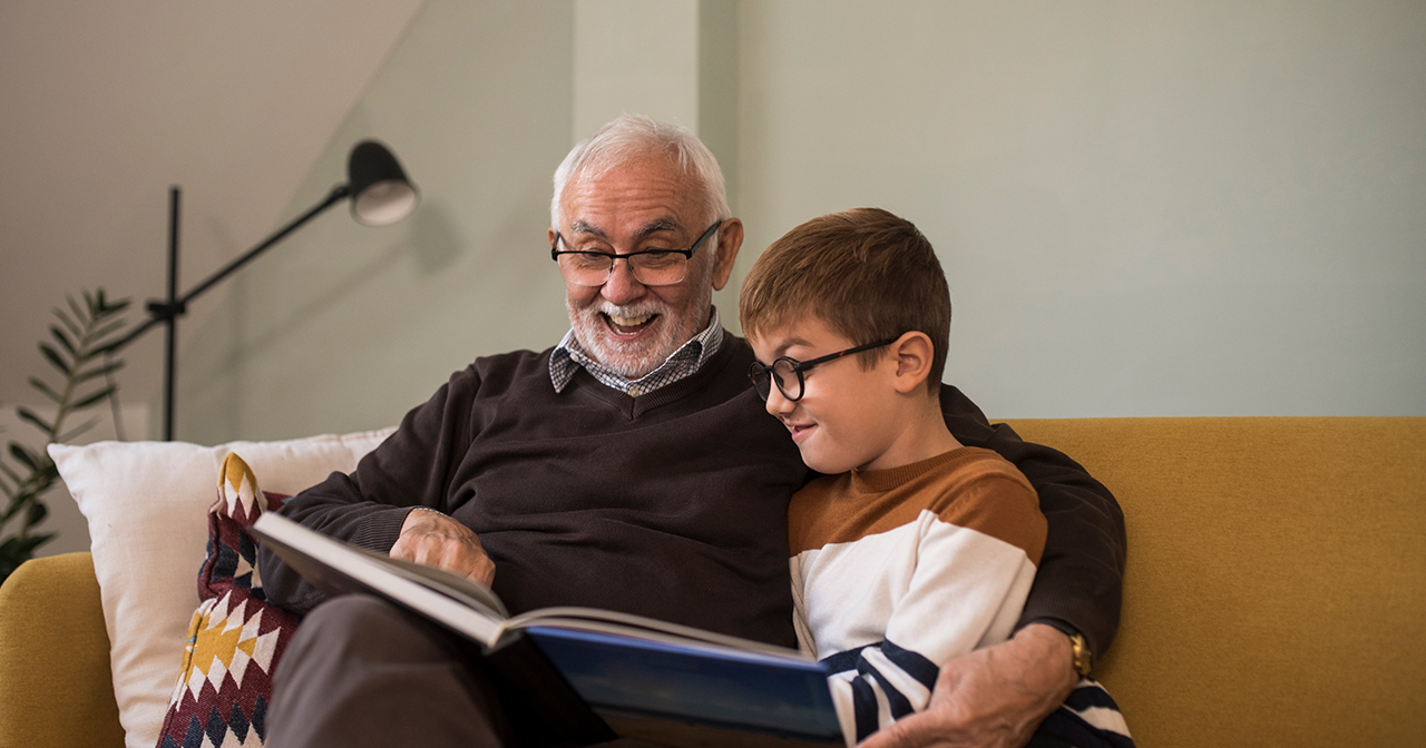Grandfather reading a book to his grandson.