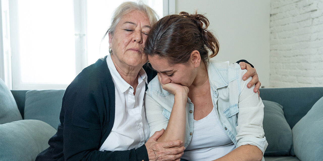 Grandmother hugging her daughter to comfort her during a moment of sadness.