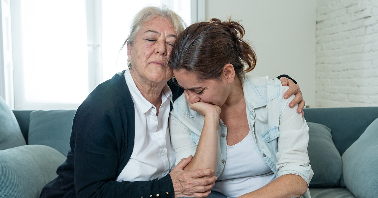 Grandmother hugging her daughter to comfort her during a moment of sadness.