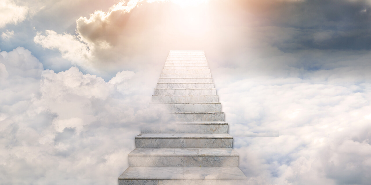 Concrete stairs leading toward sunlight breaking through the clouds.