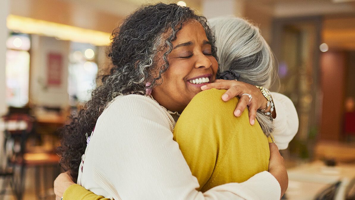 Two older women embracing each other in a warm hug.