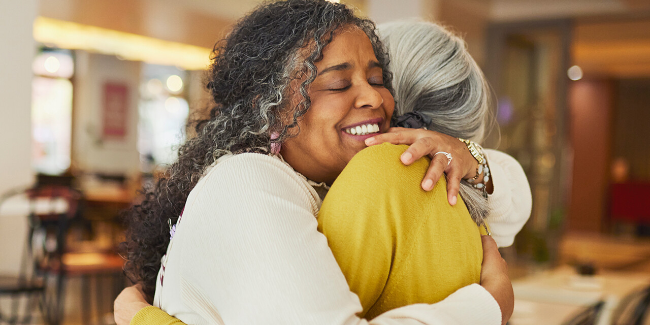 Two older women embracing each other in a warm hug.