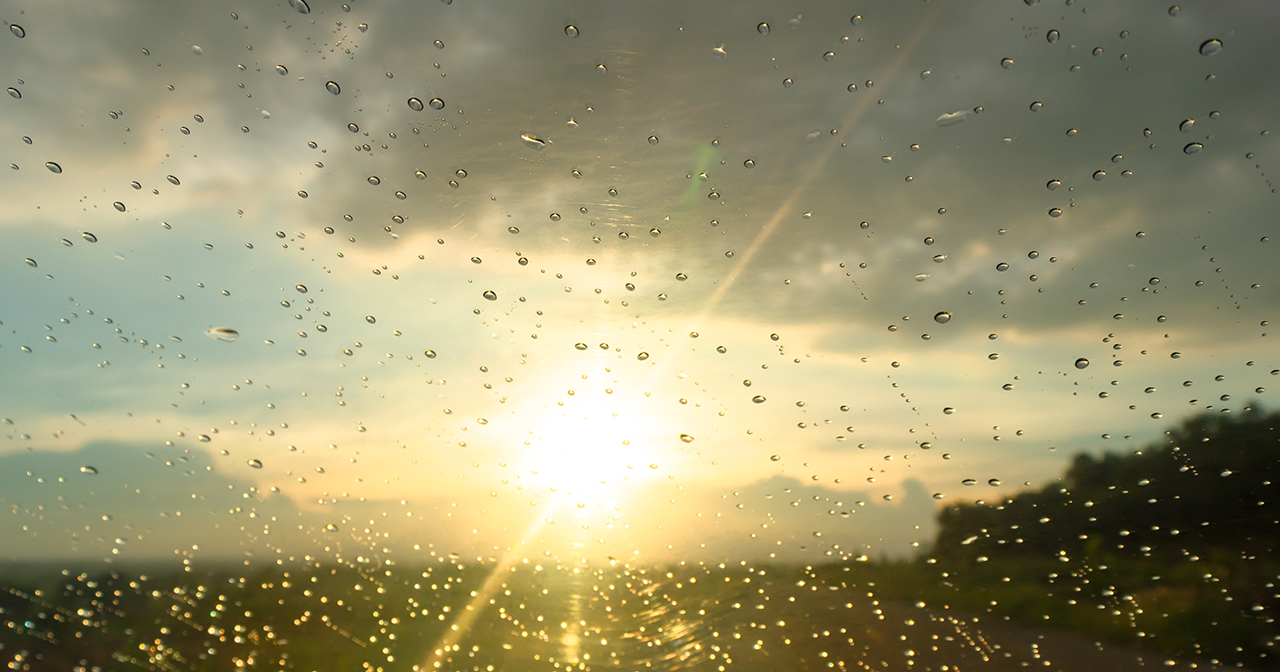 Sunlight breaking through dark rain clouds as the storm clears, revealing brighter skies.