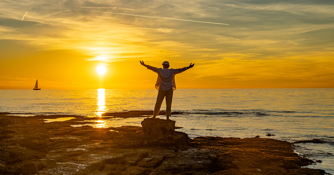 man praising God at sunset with arms raised; how to be content