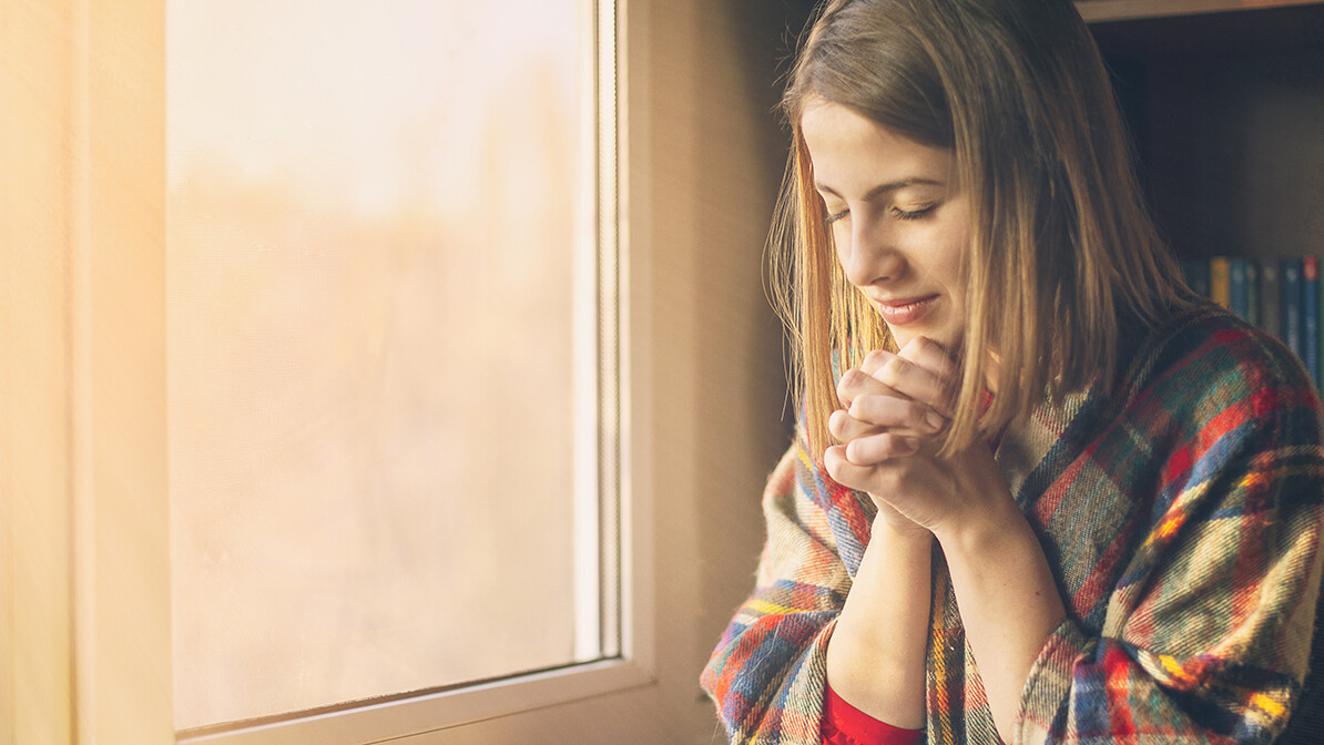 self-care, woman sitting by the window reading the Bible