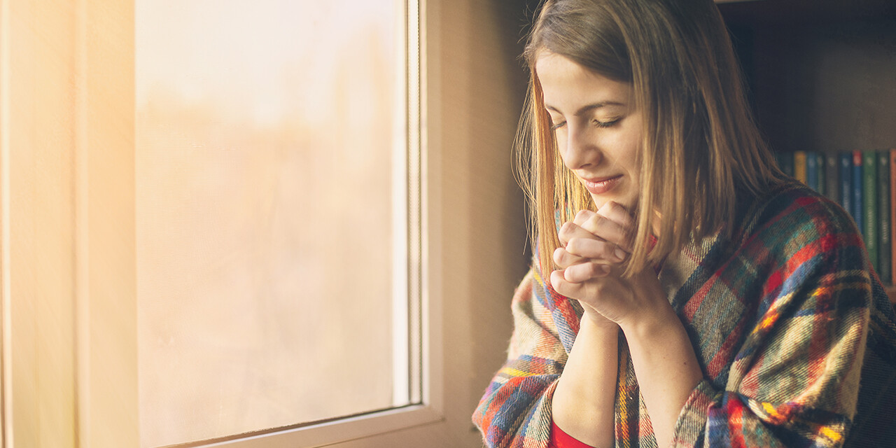 self-care, woman sitting by the window reading the Bible