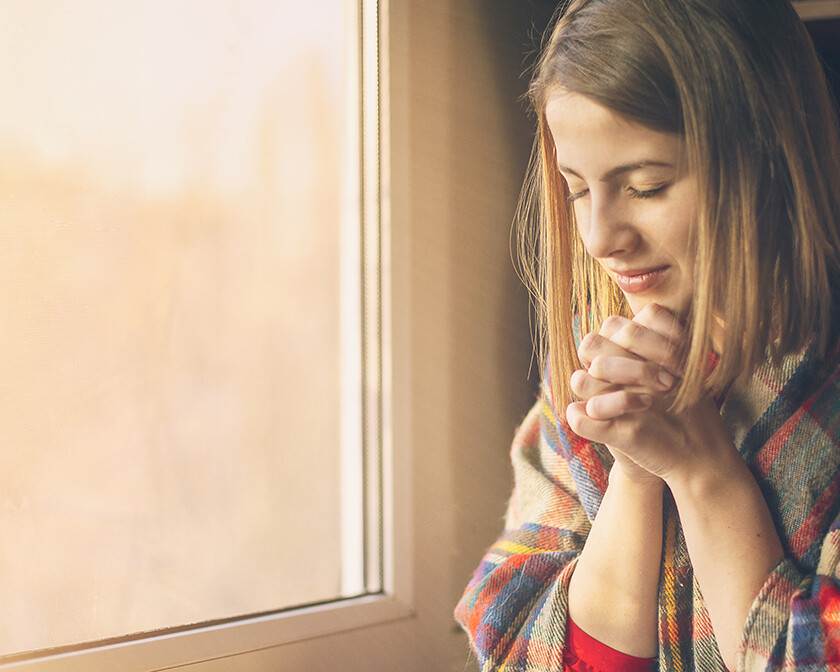 self-care, woman sitting by the window reading the Bible