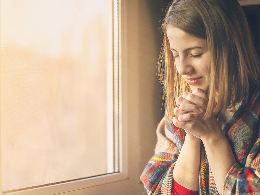 self-care, woman sitting by the window reading the Bible